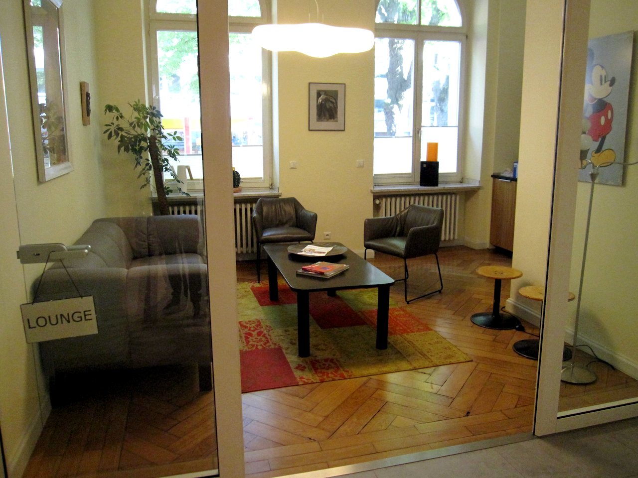Die Lounge mit Sofa und Sesseln hinter einer Glastür